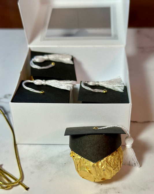 Gift box with four chocolates in graduation caps