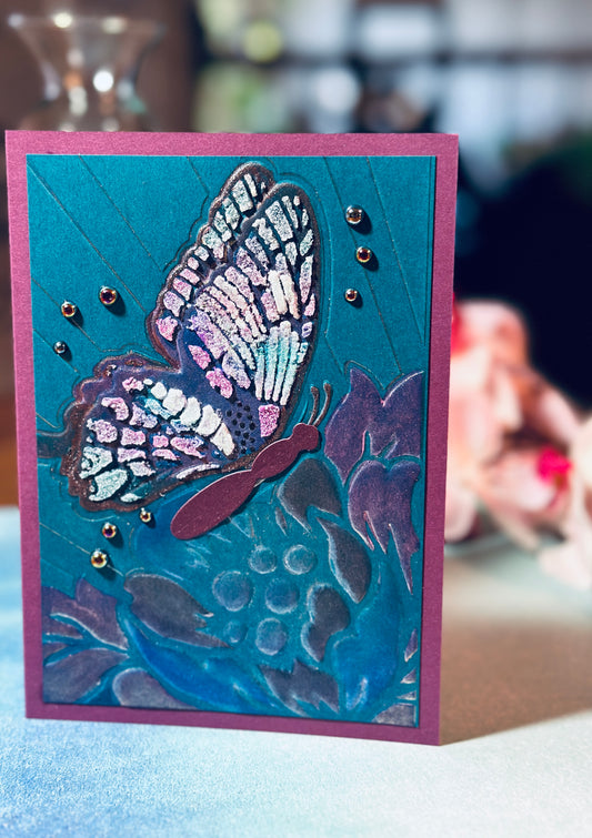 5x7 card featuring a large glitter paste butterfly in iridescent shades on a dark teal background.